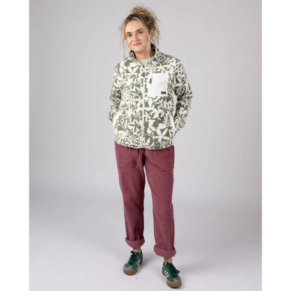 Woman wearing a Saltrock green floral patterned Balance zip fleece and maroon pants on a plain background