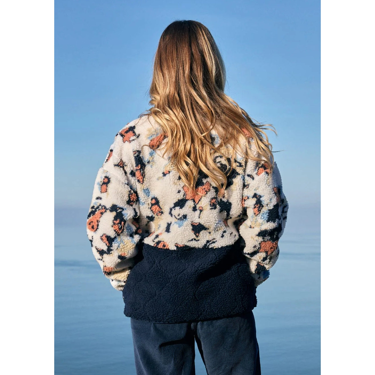 Woman wearing a patterned Saltrock Folie fleece with a blue sky background