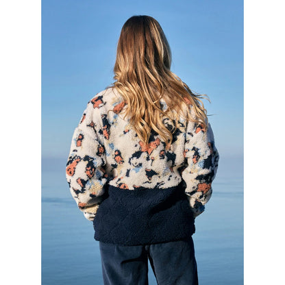 Woman wearing a patterned Saltrock Folie fleece with a blue sky background
