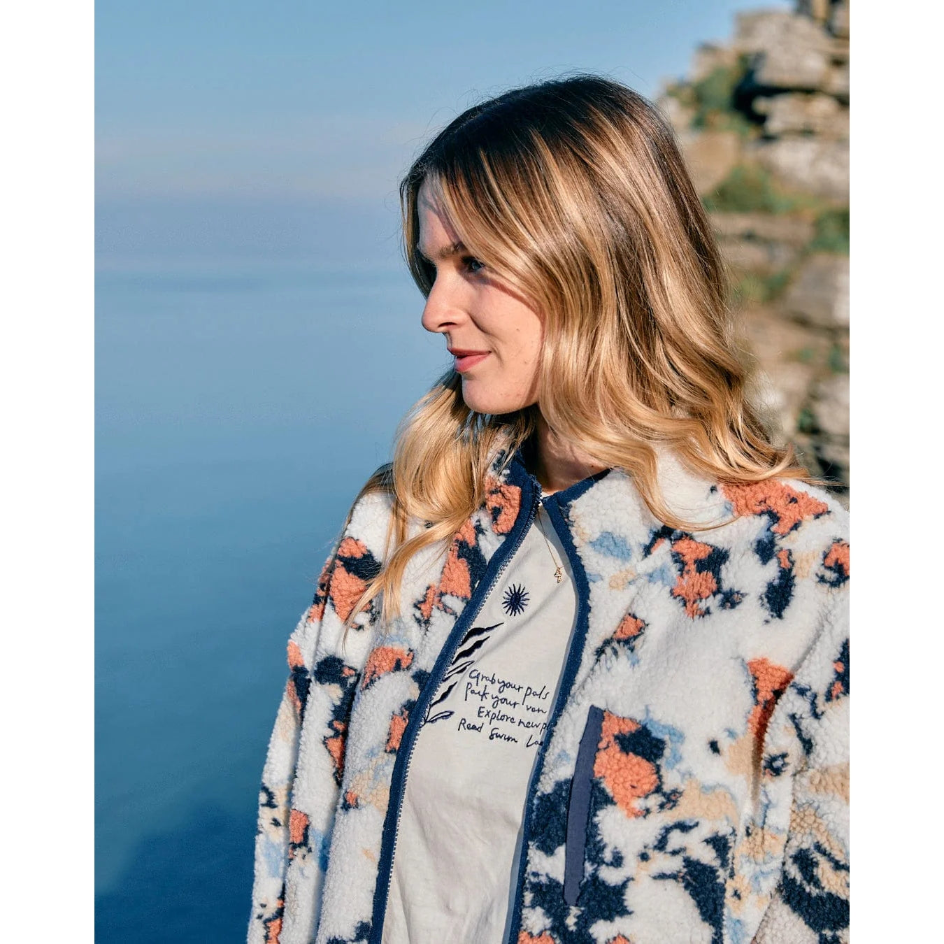 Woman wearing a printed Saltrock Folie fleece with a scenic background