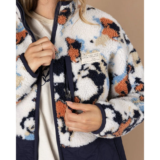 Close-up of a woman wearing a patterned Saltrock fleece with a logo on the chest.