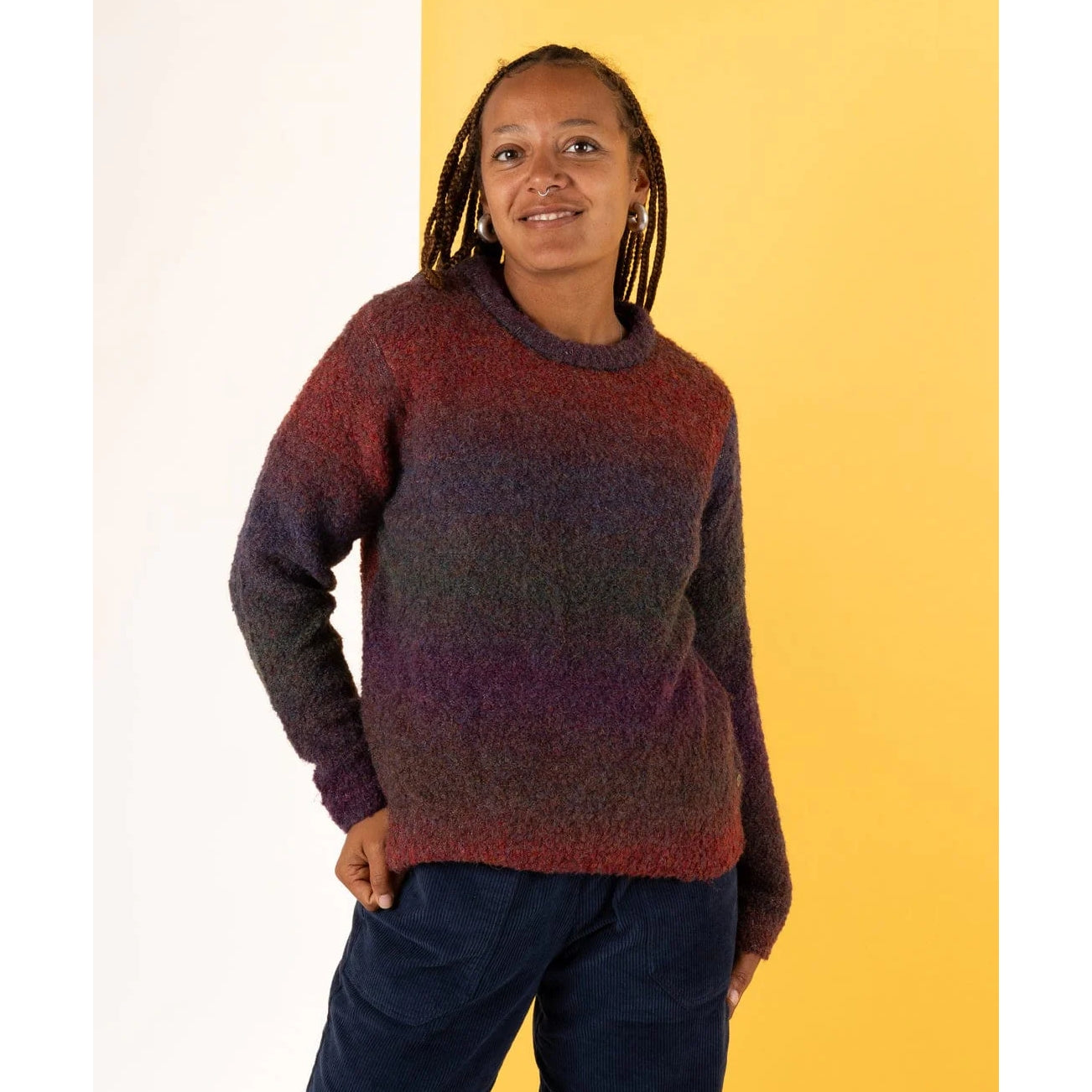 Front view of a woman wearing a Saltrock Bowden knitted crew neck jumper in Dark Purple on a yellow background.