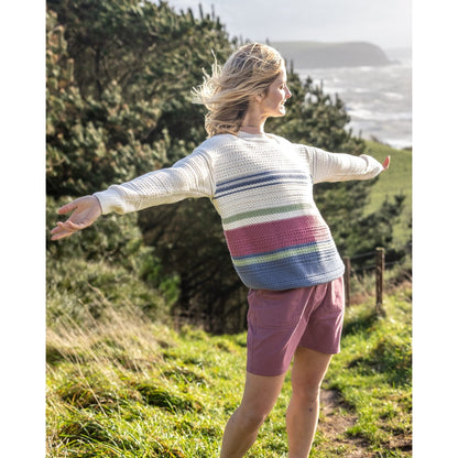 Woman wearing a Saltrok Sable colourful striped knitted jumper and pink shorts