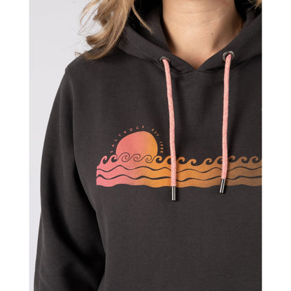 Close-up view of a woman wearing a Saltrock Golden Hour pop hoodie with a wave and sun chest print on a white background