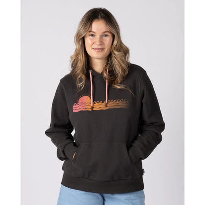 Front view of a woman wearing a dark grey Saltrock Golden Hour pop hoodie with a sun and sea chest print on a white background