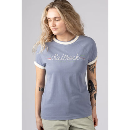 Front view of a woman wearing a blue Saltrock short sleeve Links t-shirt with embroidered chest logo on a grey background