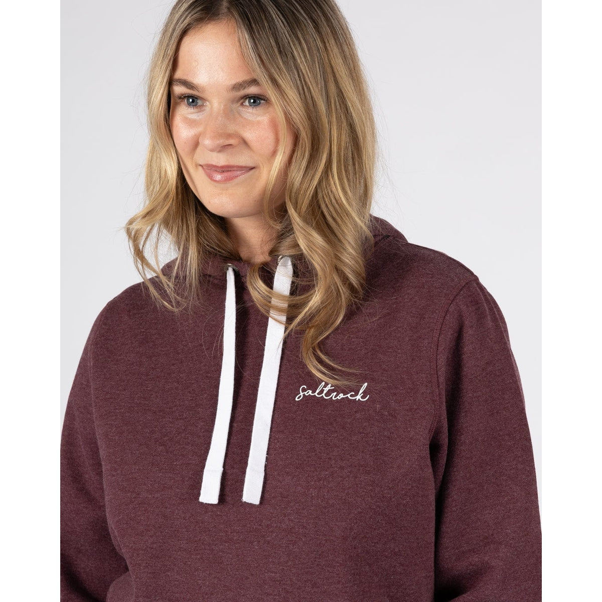 Close-up view of a woman wearing a Saltrock Velator hoodie in Dark Purple, with white hood drawstring and small logo on the chest.
