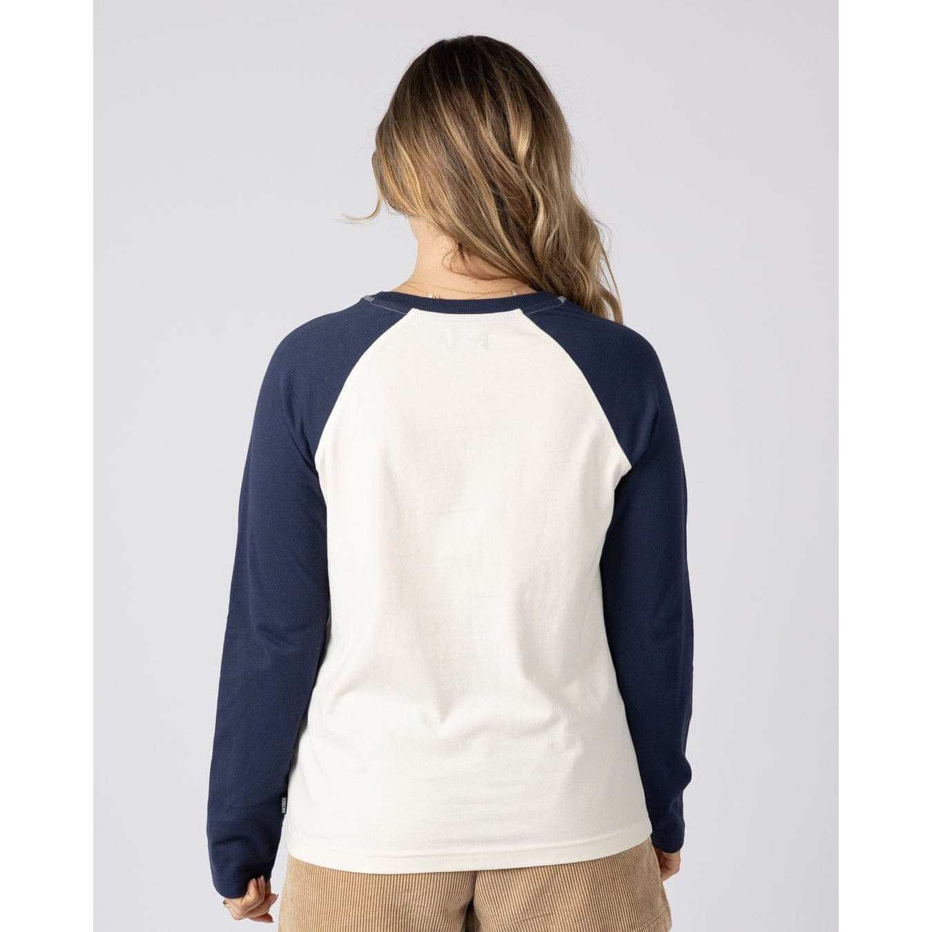 Back view of a woman wearing a Saltrock long sleeve Golden Hour t-shirt in cream with navy blue raglan sleeves