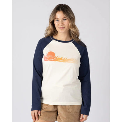 Front view of a woman wearing a Saltrock long sleeve raglan t-shirt in cream with navy sleeves and a Golden Hour sunset and sea chest print on a white background