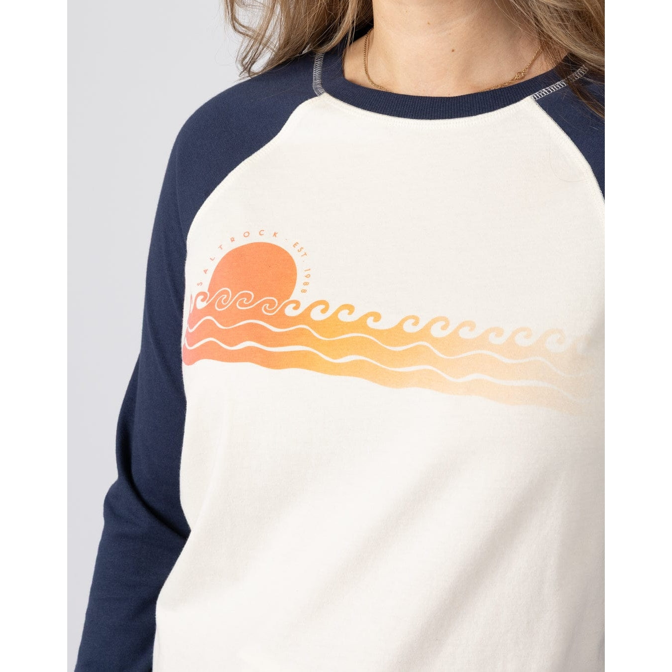 Close-up view of a Saltrock womens Gold Hour raglan t-shirt in cream and navy, featuring a sunset and sea printed chest design