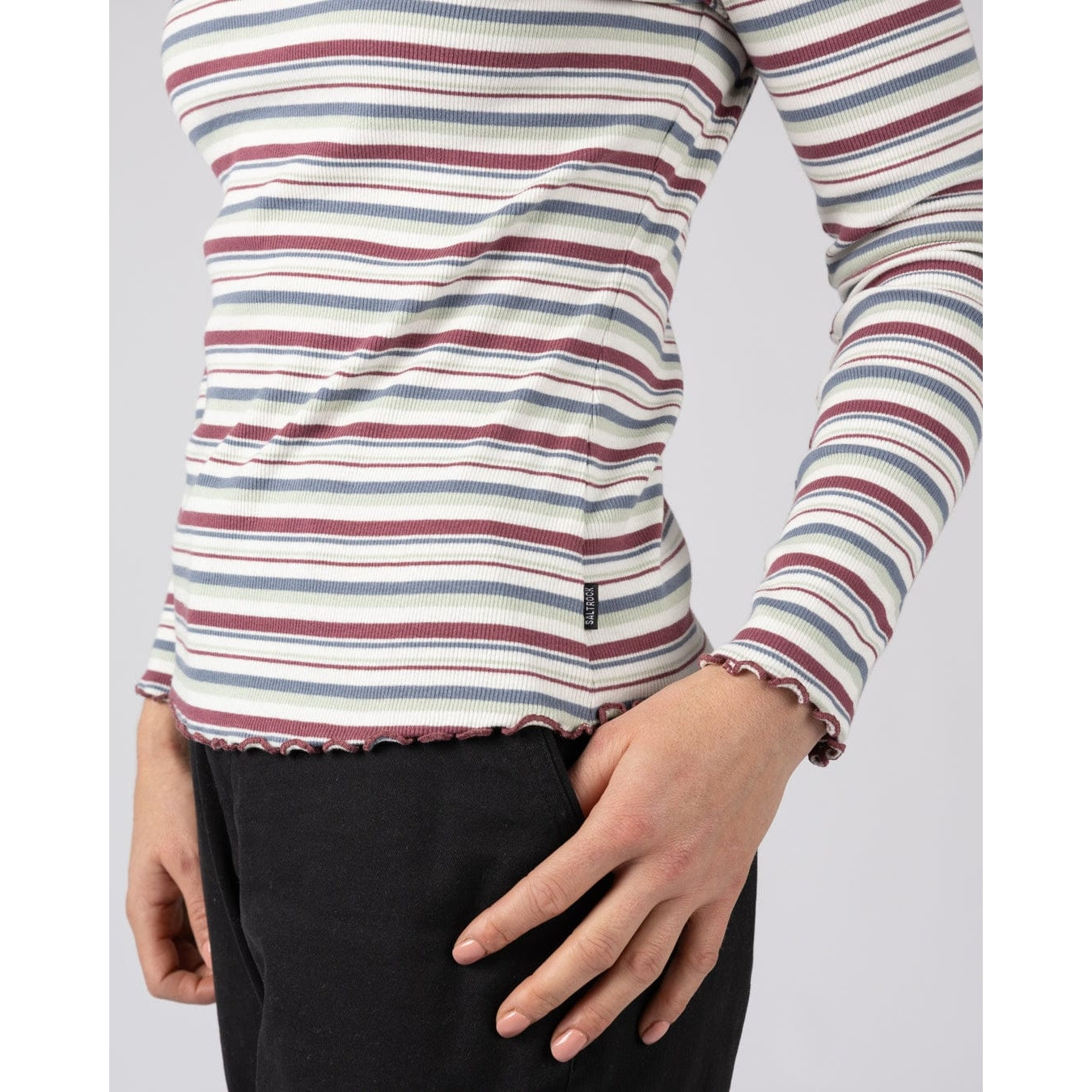 Close-up view of a womens Saltrock long sleeve Lenna t-shirt in white with a multicolour stripe pattern and lettuce finish cuffs and hem