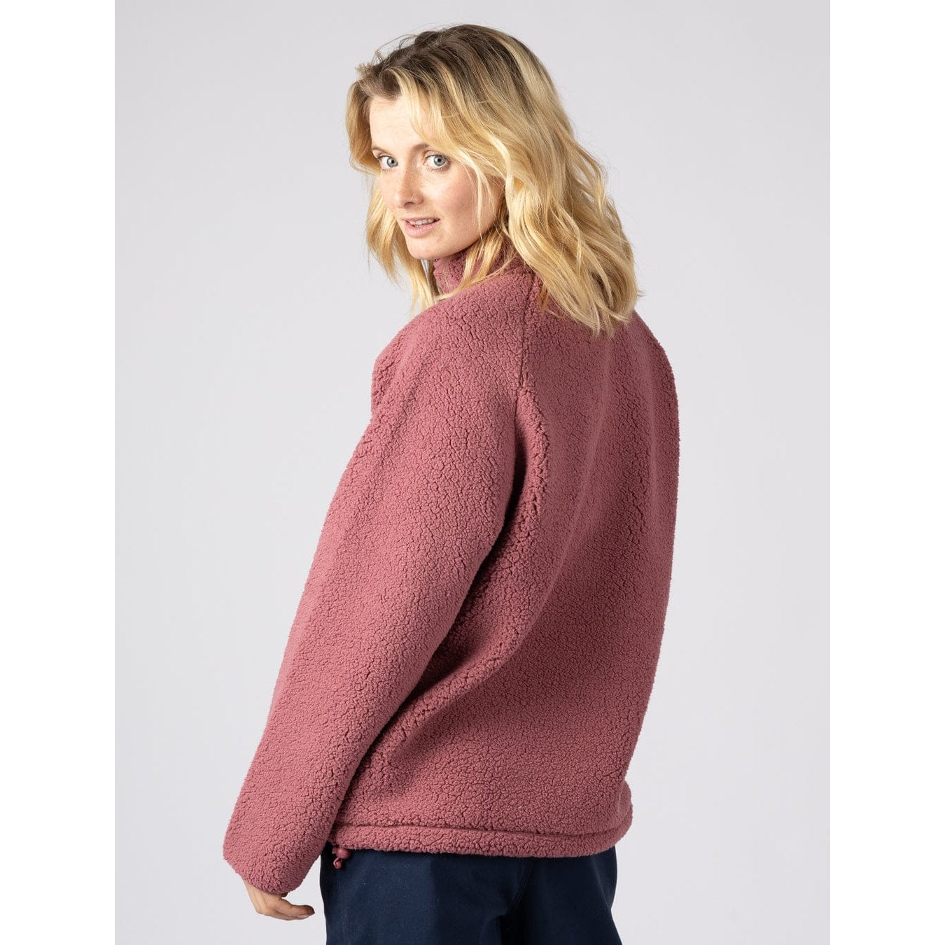 Back view of a woman wearing a Saltrock Lya fleece in dark pink on a plain background