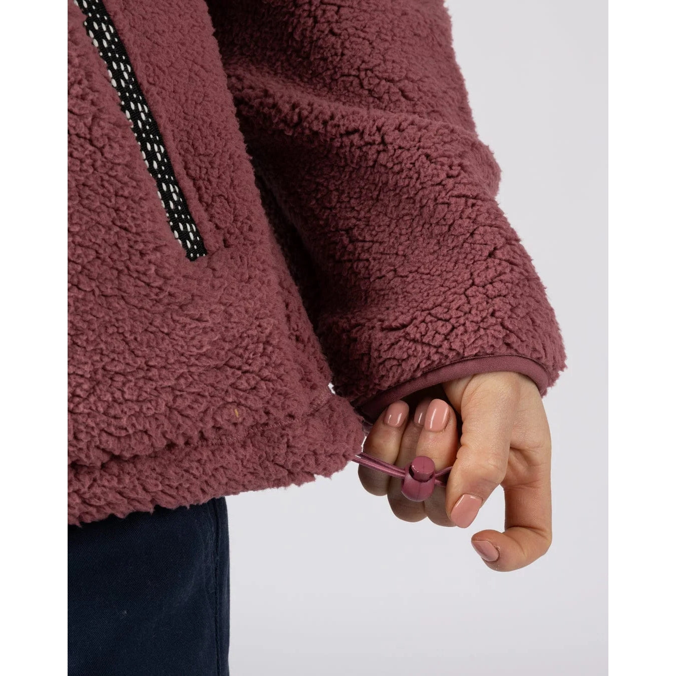 Close-up of woman wearing a dark pink Saltrock Lya fleece with adjustable hem toggle on a white background
