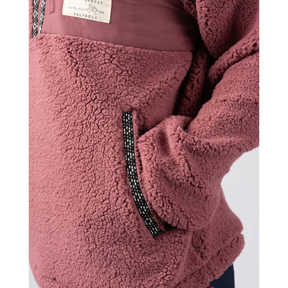 Close-up of a dark pink Saltrock Lya fleece with a brand label and tummy pocket on a white background