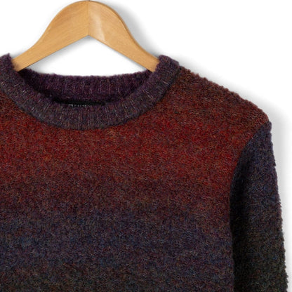Closeup of the neckline of a Saltrock womens Bowden jumper with a purple and red gradient pattern on a wooden hanger against a white background
