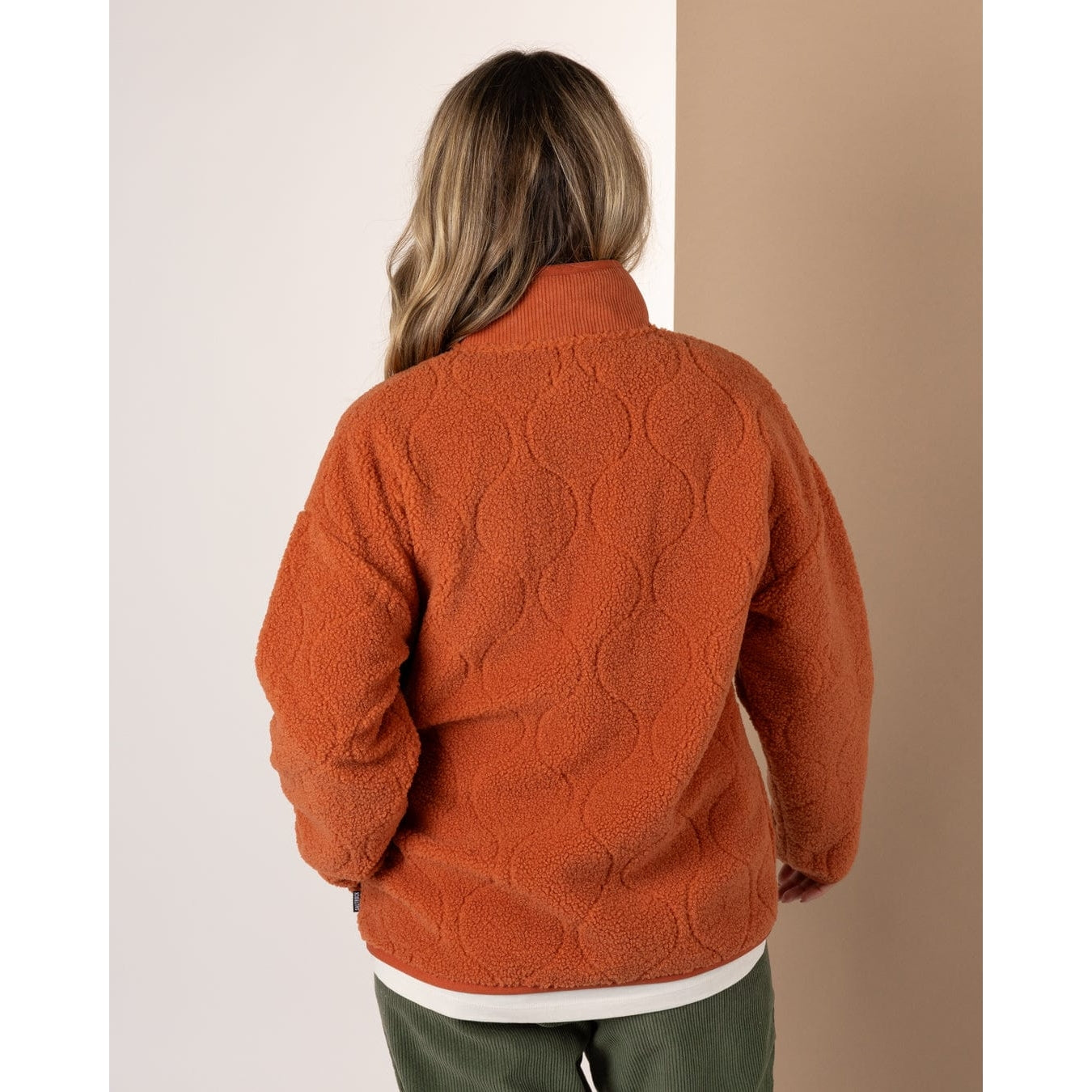 Woman wearing an orange Saltrock Jarvis fleece against a neutral background