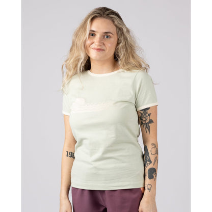 Front view of a woman wearing a light green Saltrock Golden Hour short sleeve t-shirt with sunset and sea print across the chest with burgundy shorts against a plain background