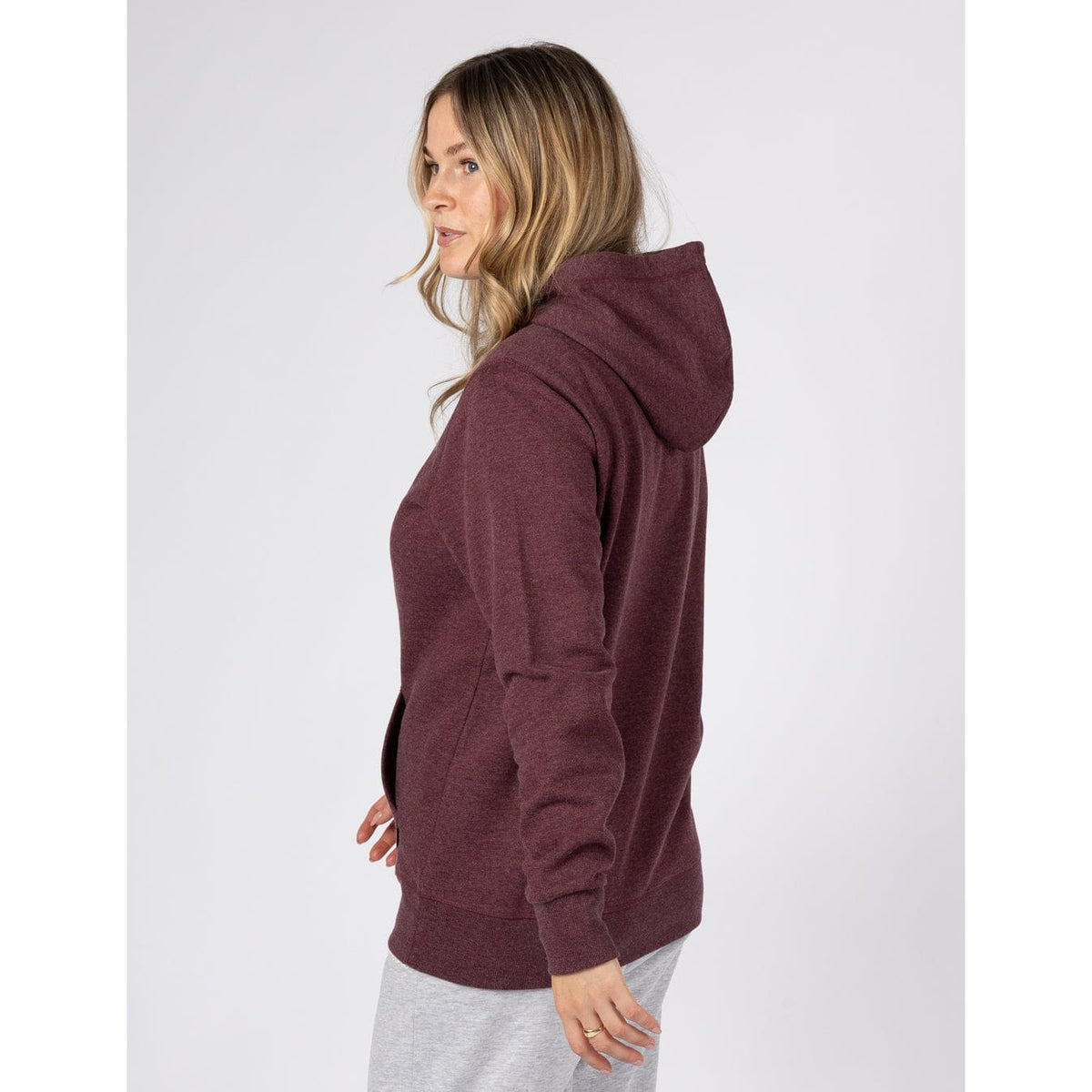 Side view of a woman wearing a Saltrock Velator hoodie in Dark Purple.