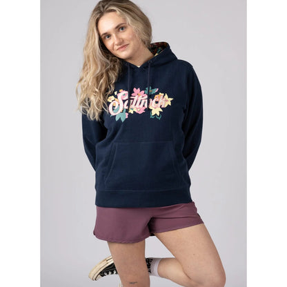 Front view of a woman wearing a navy Saltrock pop hoodie with floral logo design on a plain background