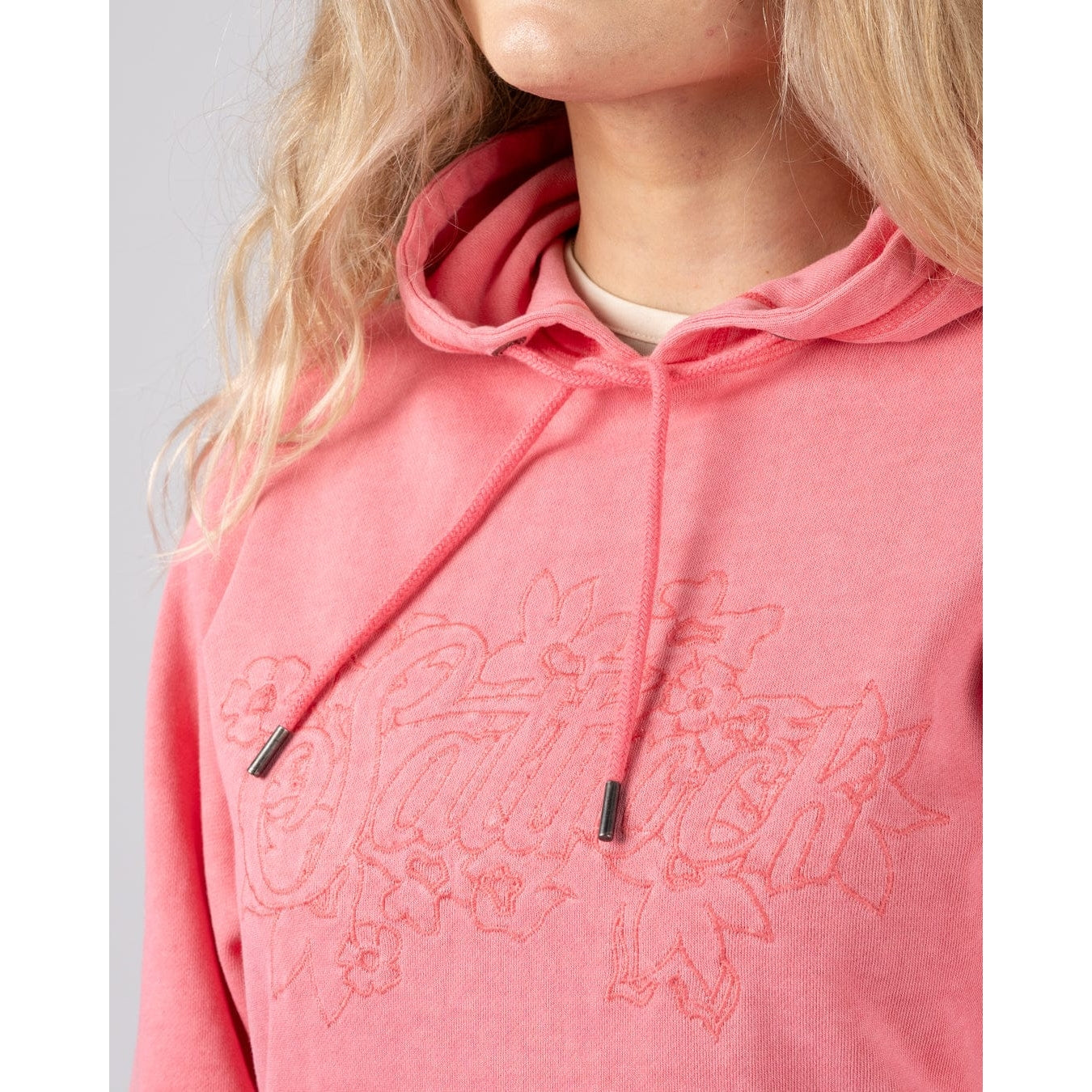 Close-up vie of a Saltrock womens Trader Tonal bright pink pop hoodie with embroidered chest logo on a plain background