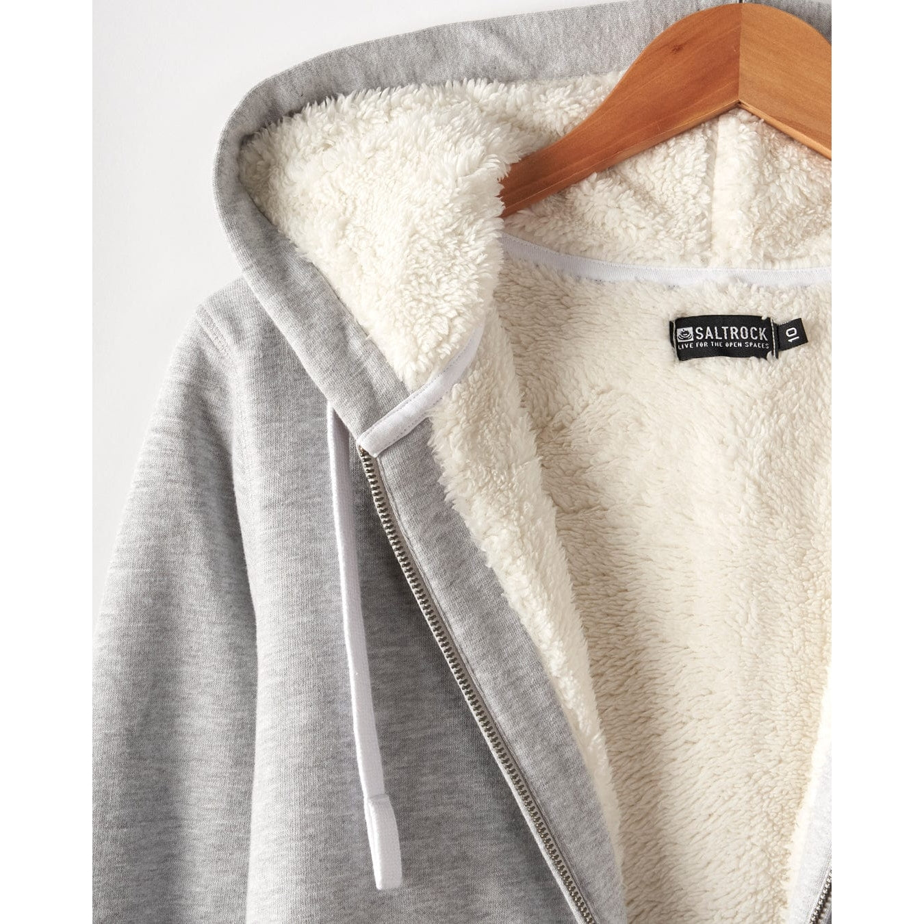 Close-up view of a Saltrock womens full zip Velator grey hoodie with white borg lining on a hanger, featuring a 'Saltrock' brand label.