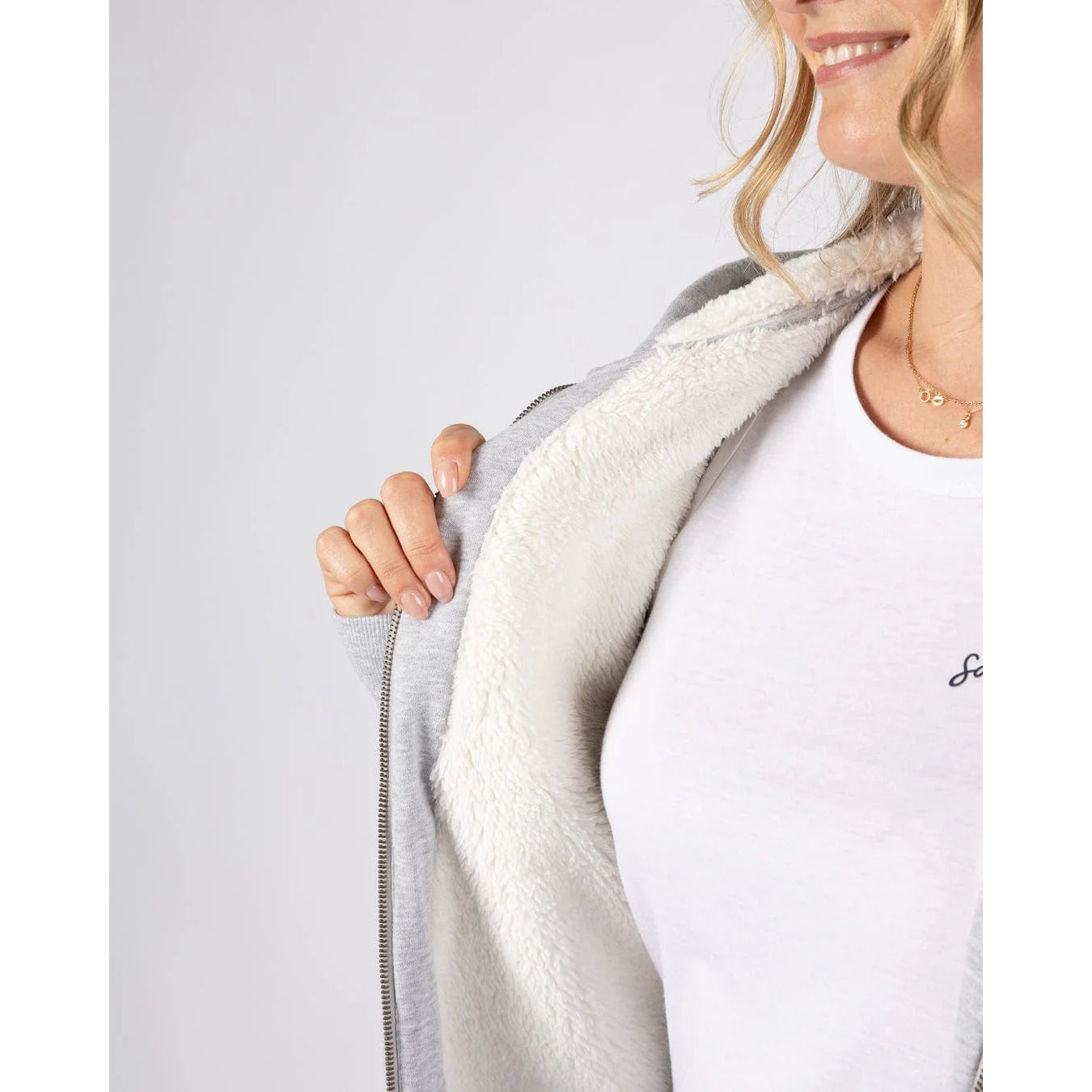 Close-up of a woman wearing a Saltrock grey borg lined Velator hoodie and a white t-shirt underneath on a light grey background