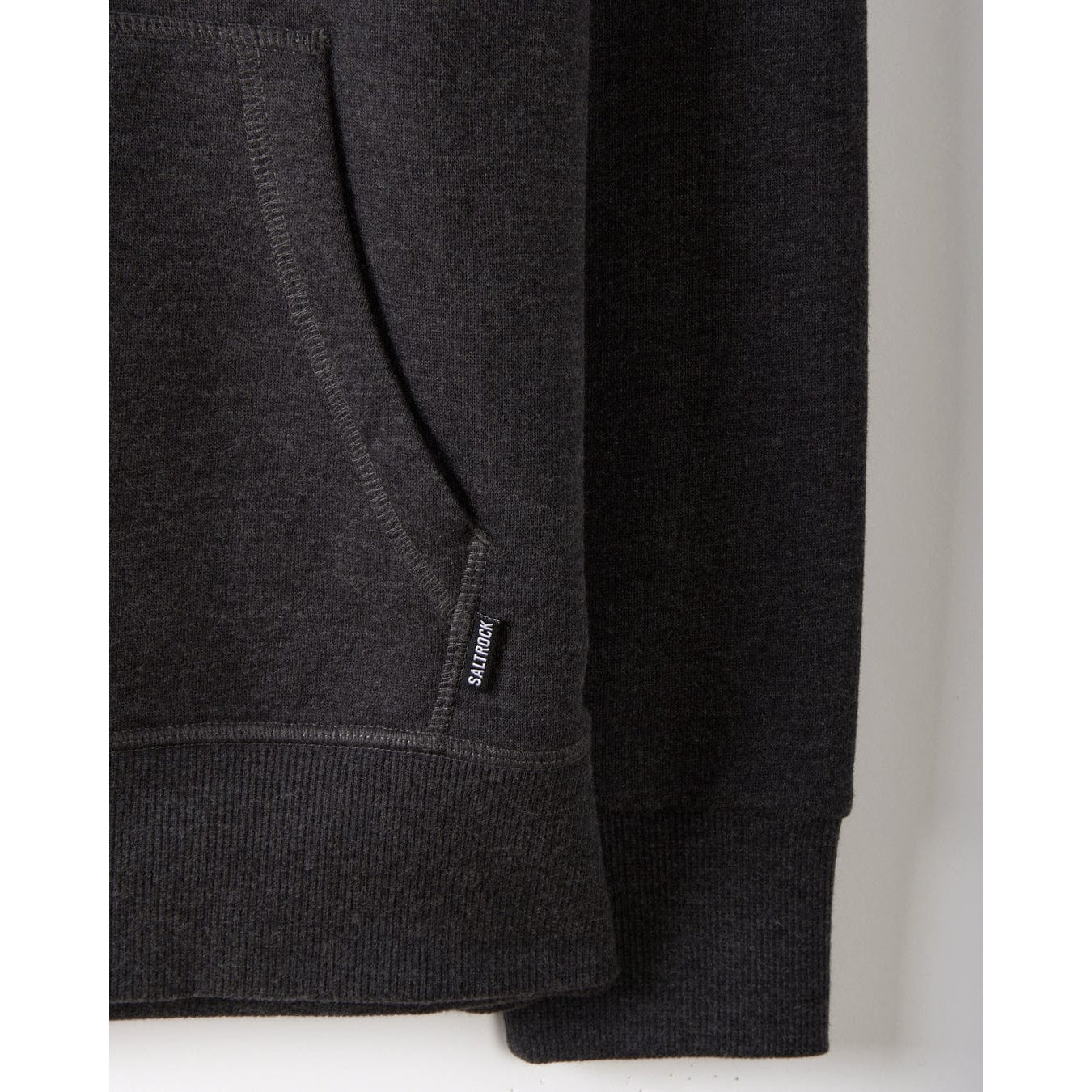 Dark grey womens Saltrock pop hoodie with a brand logo and tummy pocket on a light grey background