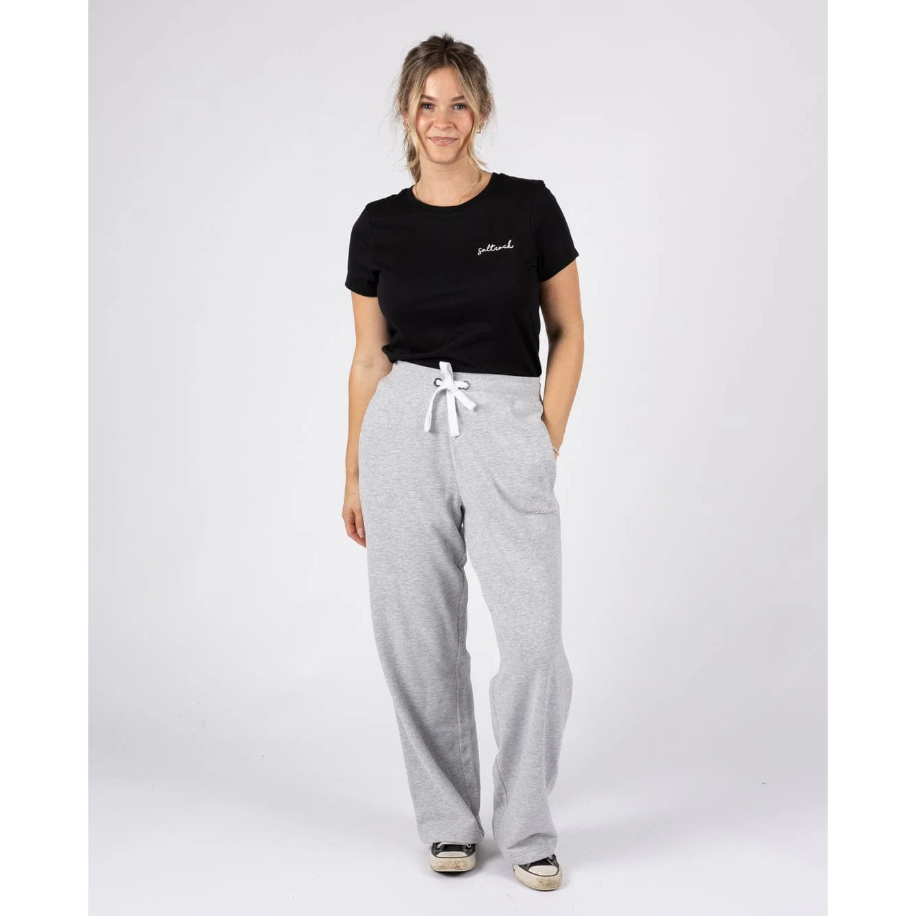 Woman wearing a pair of Saltrock sweat trousers in grey with drawstring waist, with a black t-shirt.