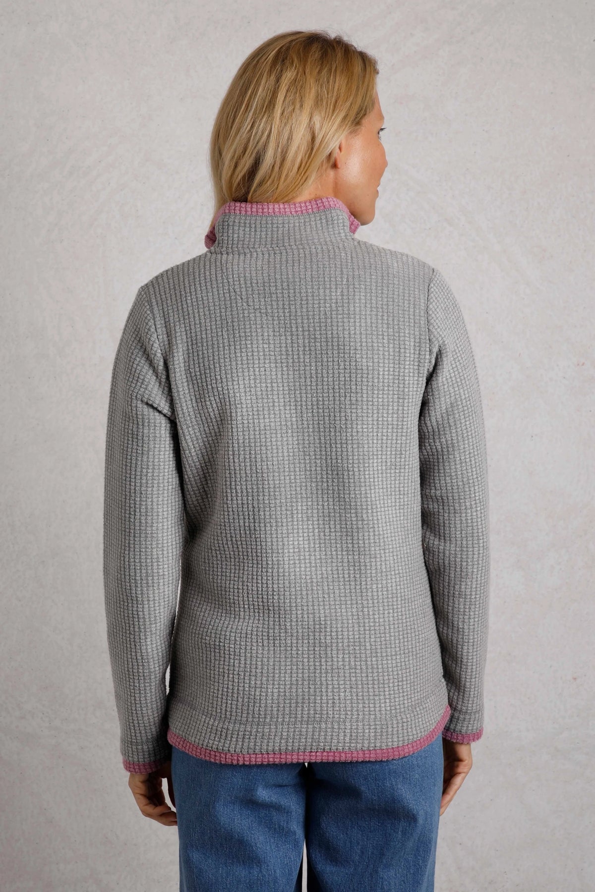 Back view of a woman wearing a Frost Grey Weird Fish Beye grid fleece with pink trim.