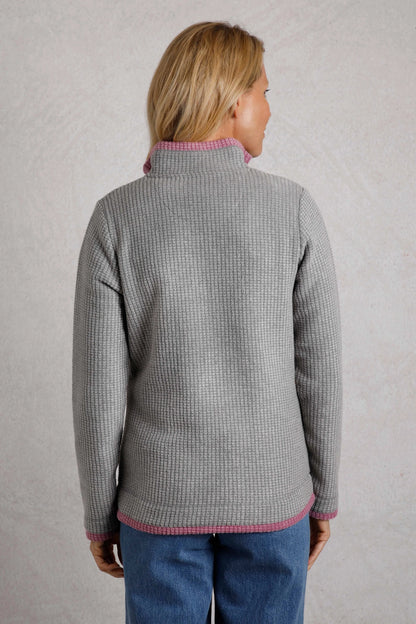 Back view of a woman wearing a Frost Grey Weird Fish Beye grid fleece with pink trim.