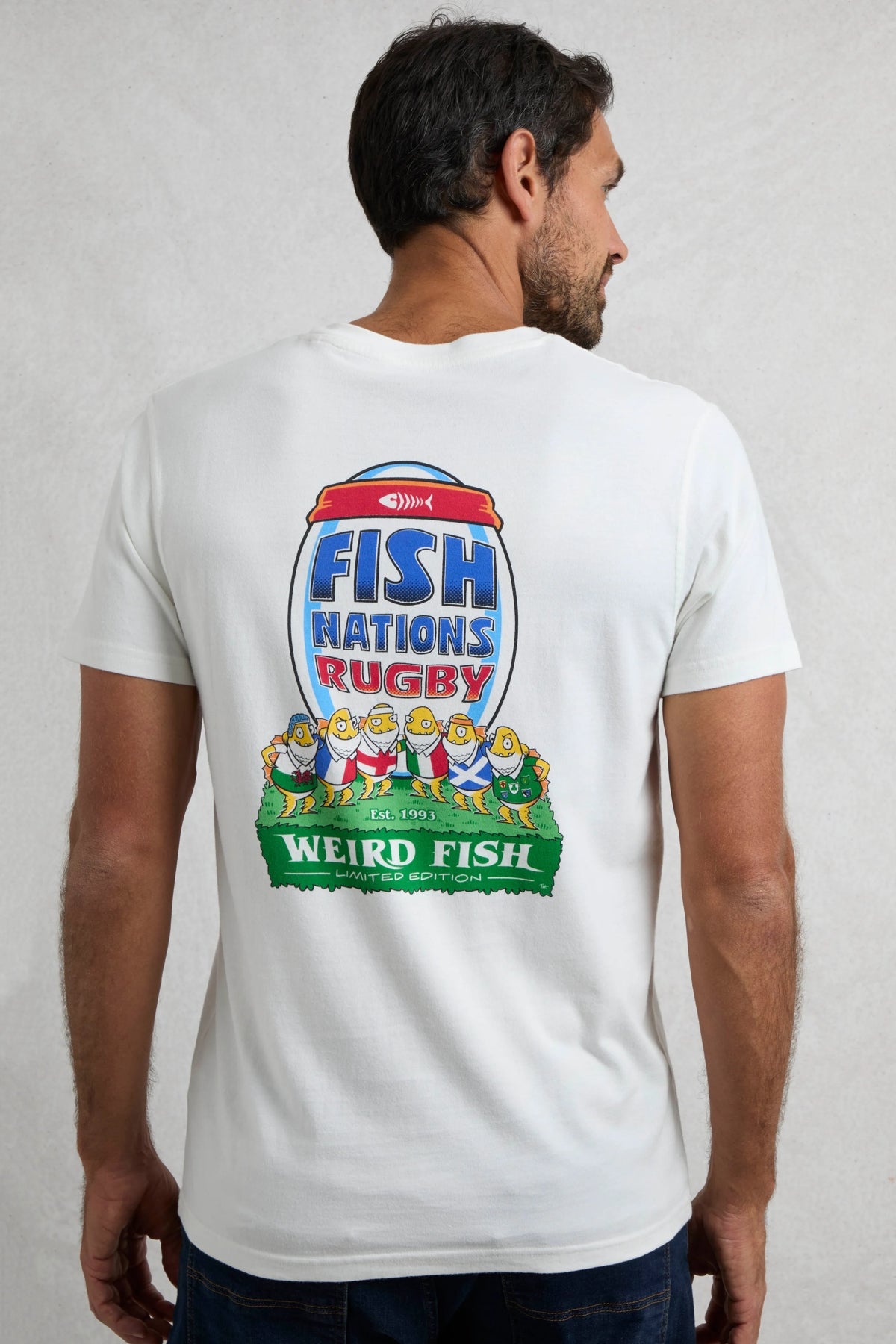 Man wearing a Weird Fish short sleeve white t-shirt featuring a large rugby themed Fish Nations print on the back on a white background