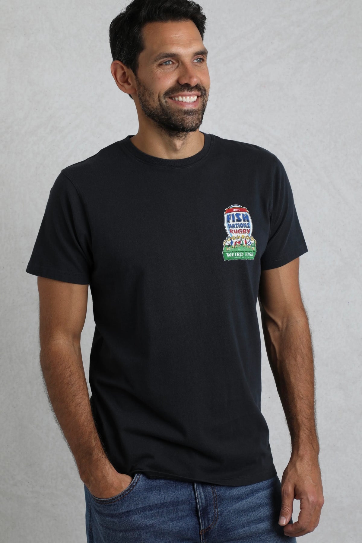 A man wearing a navy Weird Fish short sleeve t-shirt with a rugby themed Six Nations print on a light grey background