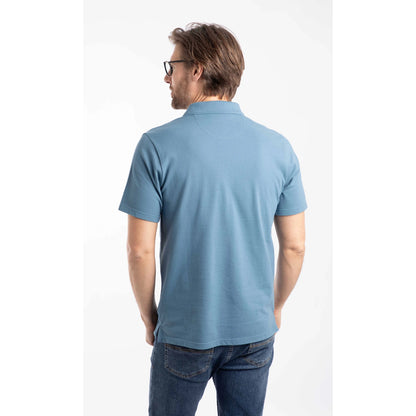 Back view of a man wearing a short sleeve Weird Fish Miles pique polo shirt in Faded Blue.