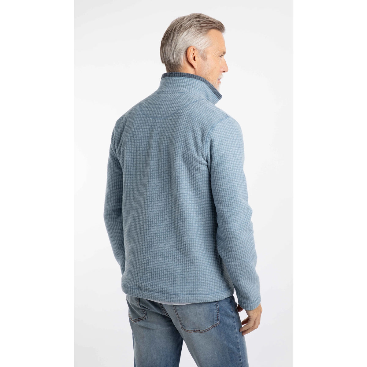 Back view of a man wearing a Weird Fish Newark 1/4 zip grid fleece in light blue, with blue jeans