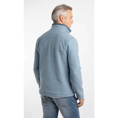 Back view of a man wearing a Weird Fish Newark 1/4 zip grid fleece in light blue, with blue jeans