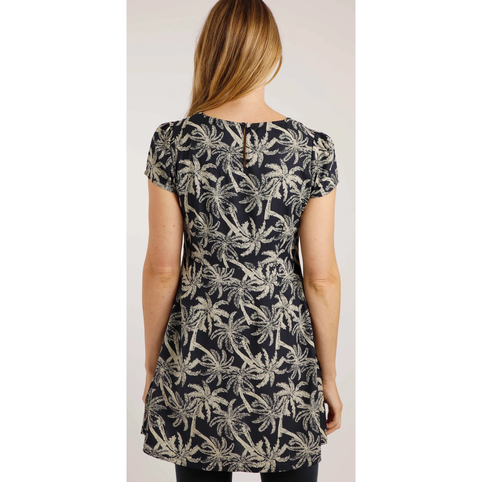 Back view of a woman wearing a Weird Fish short sleeve Breeza tunic in Midnight Navy with a beige palm tree pattern.