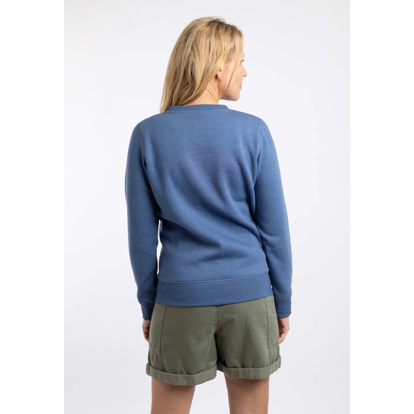 Back view of a woman wearing a Weird Fish Aurora crew neck sweatshirt in Faded Blue with a nautical logo print on the front.