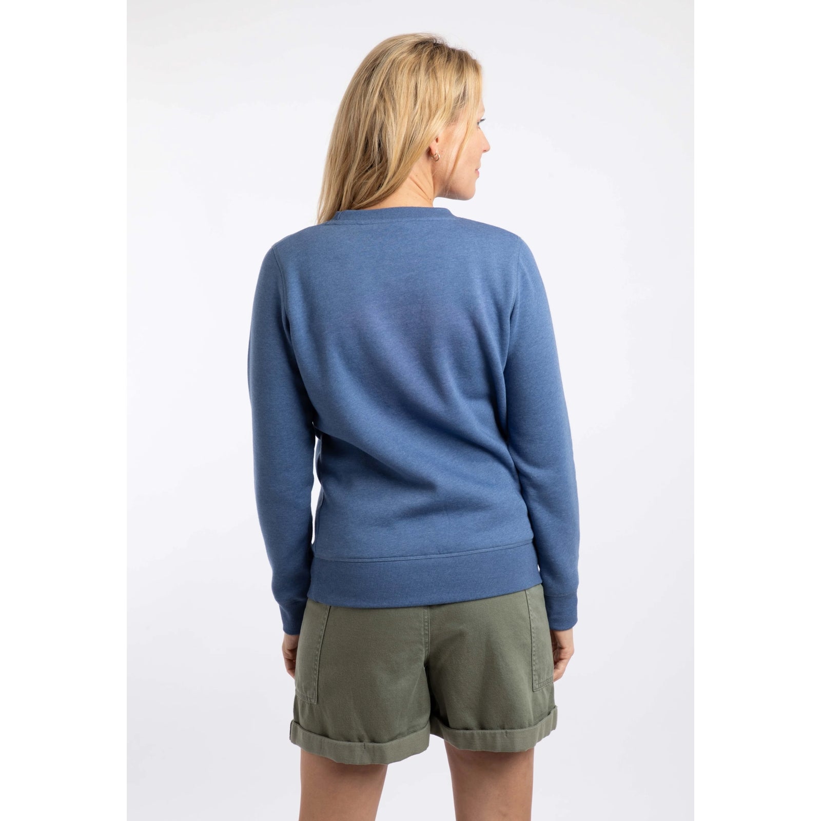 Back view of a woman wearing a Weird Fish Aurora crew neck sweatshirt in Faded Blue with a nautical logo print on the front.