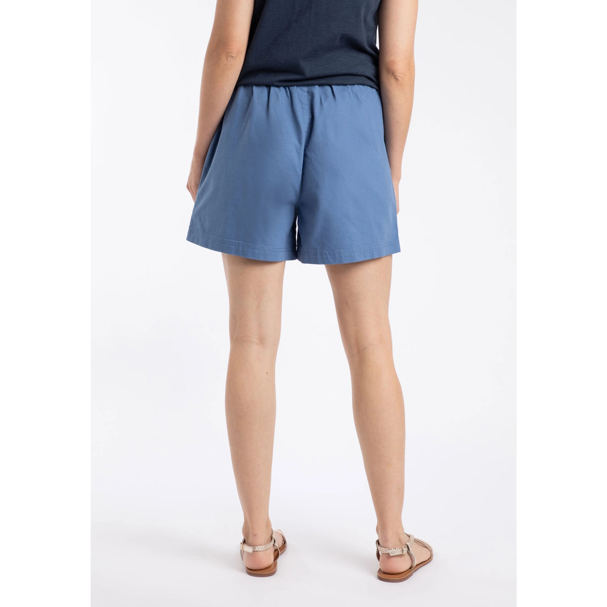 Back view of a woman wearing a pair of Weird Fish Jardin elastic waist twill cotton shorts in Faded Blue with hip pockets.