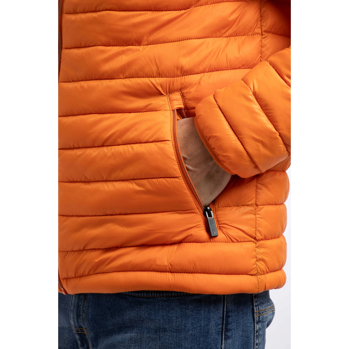 Close-up view of a front tummy pocket of a Weird Fish Crantock padded lightweight showerproof jacket in bright Koi Orange.
