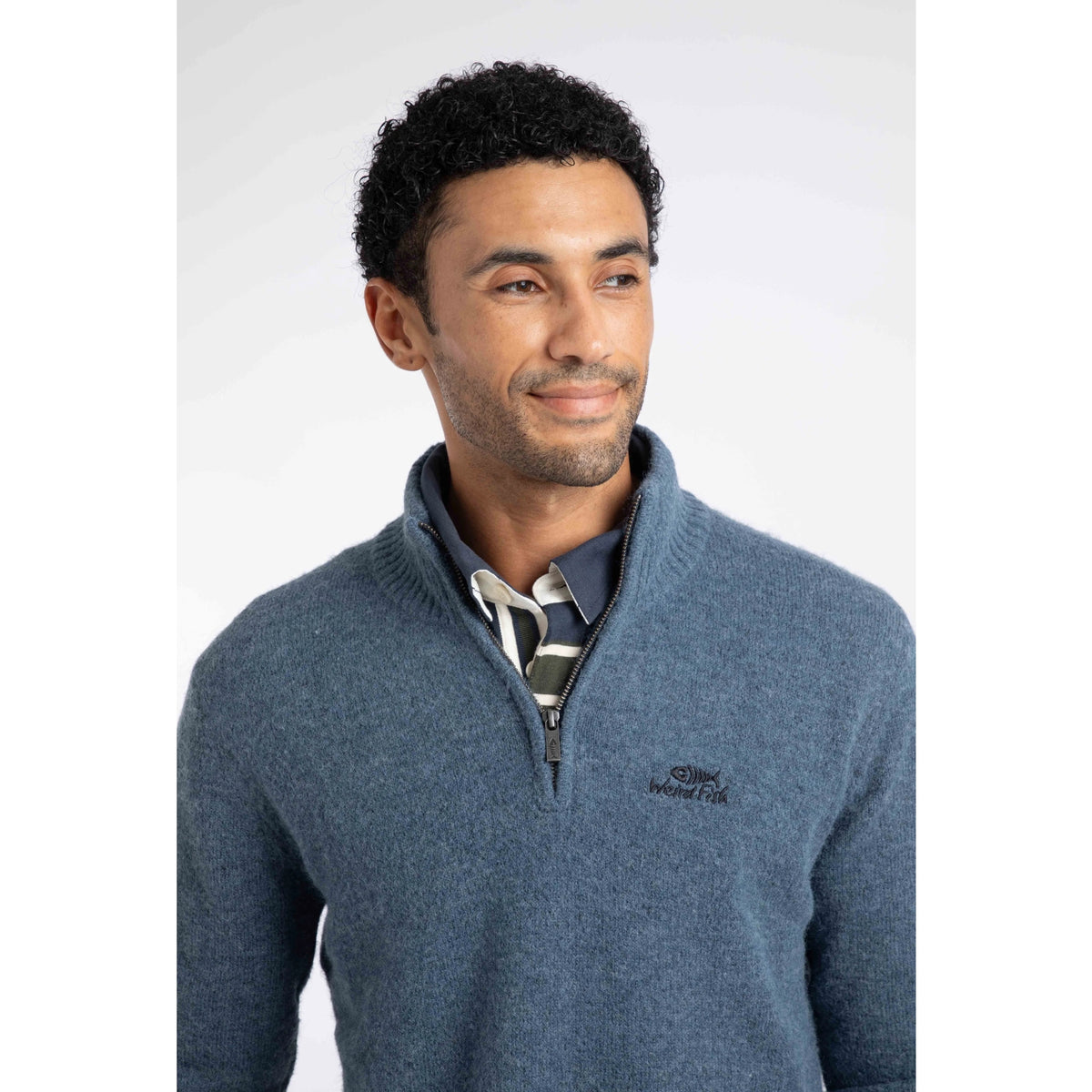 Close-up view of a man wearing a Weird Fish 1/4 zip Altwood knitted jumper in Ash Blue.