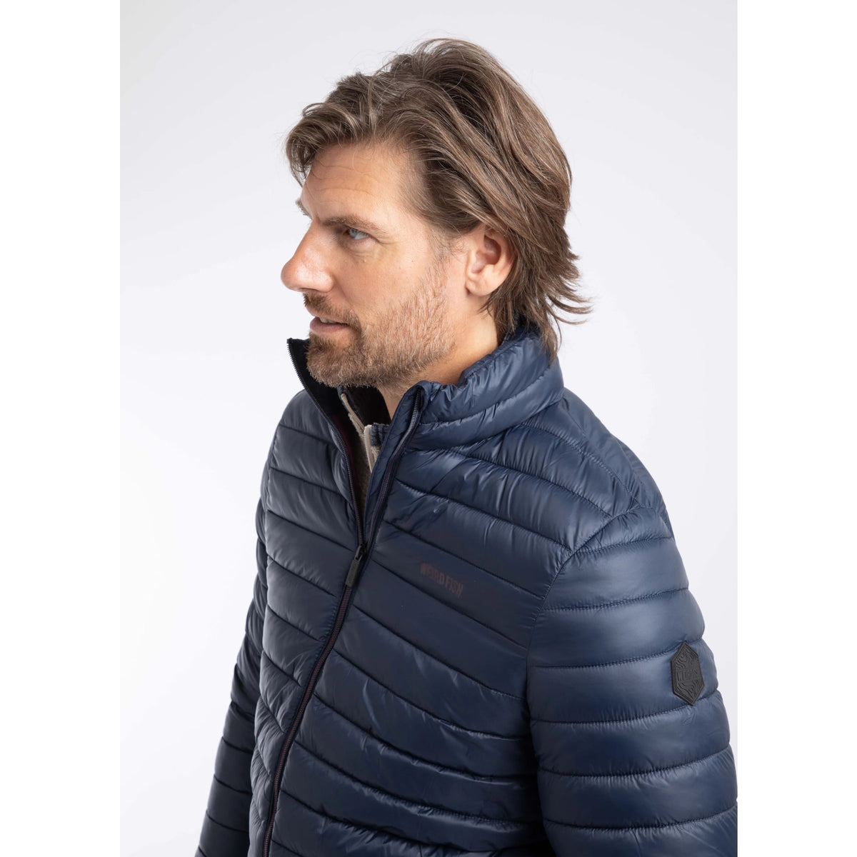 Close-up view of a man wearing a Weird Fish Crantock padded jacket in navy.