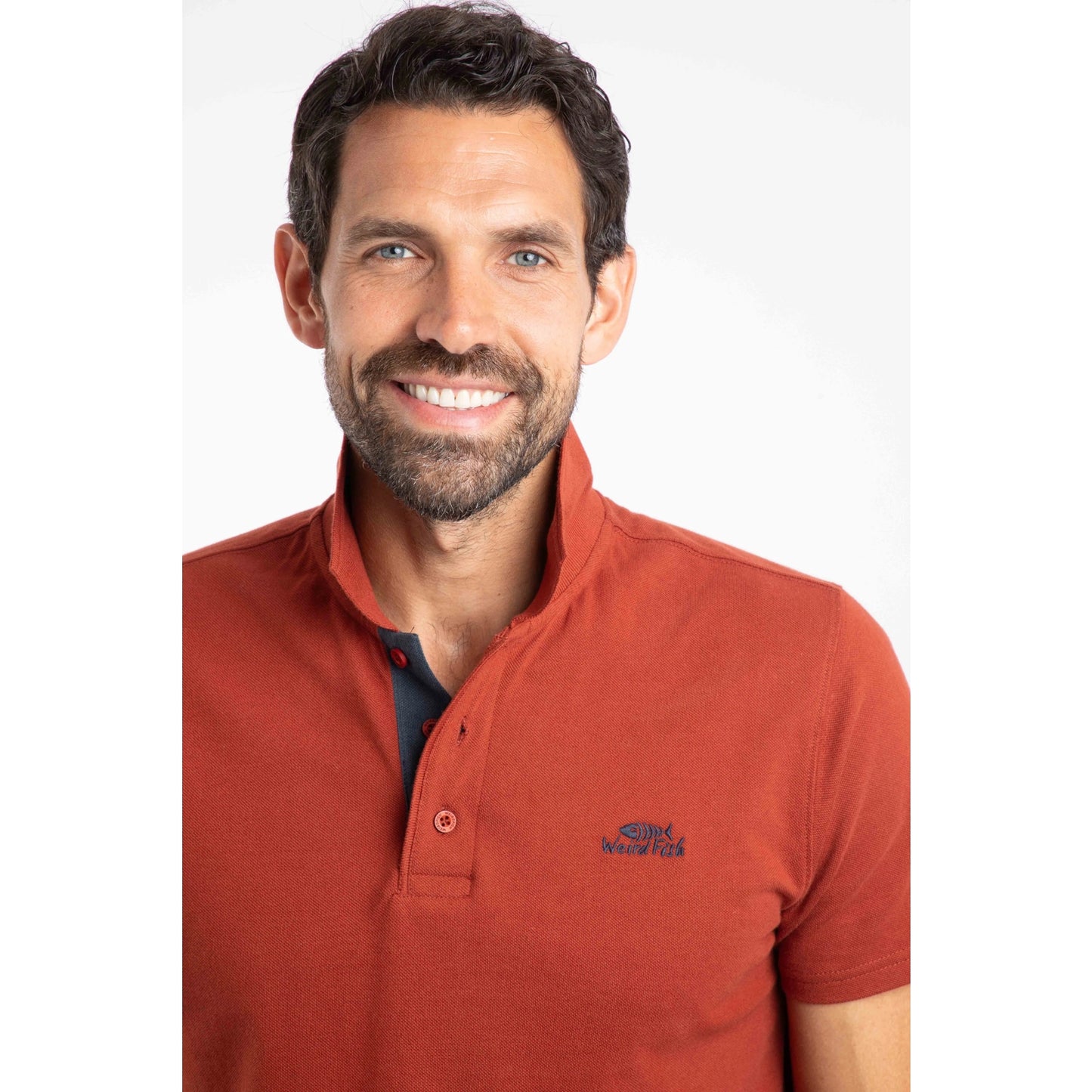 Close-up view of a man wearing a short sleeve Weird Fish Miles polo shirt in Burnt Henna.