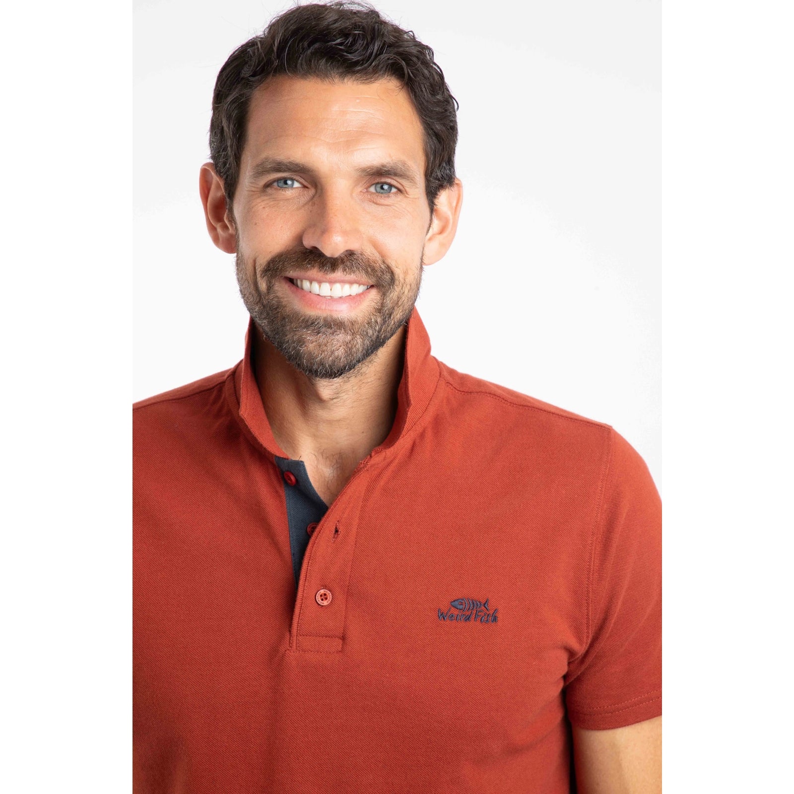 Close-up view of a man wearing a short sleeve Weird Fish Miles polo shirt in Burnt Henna.