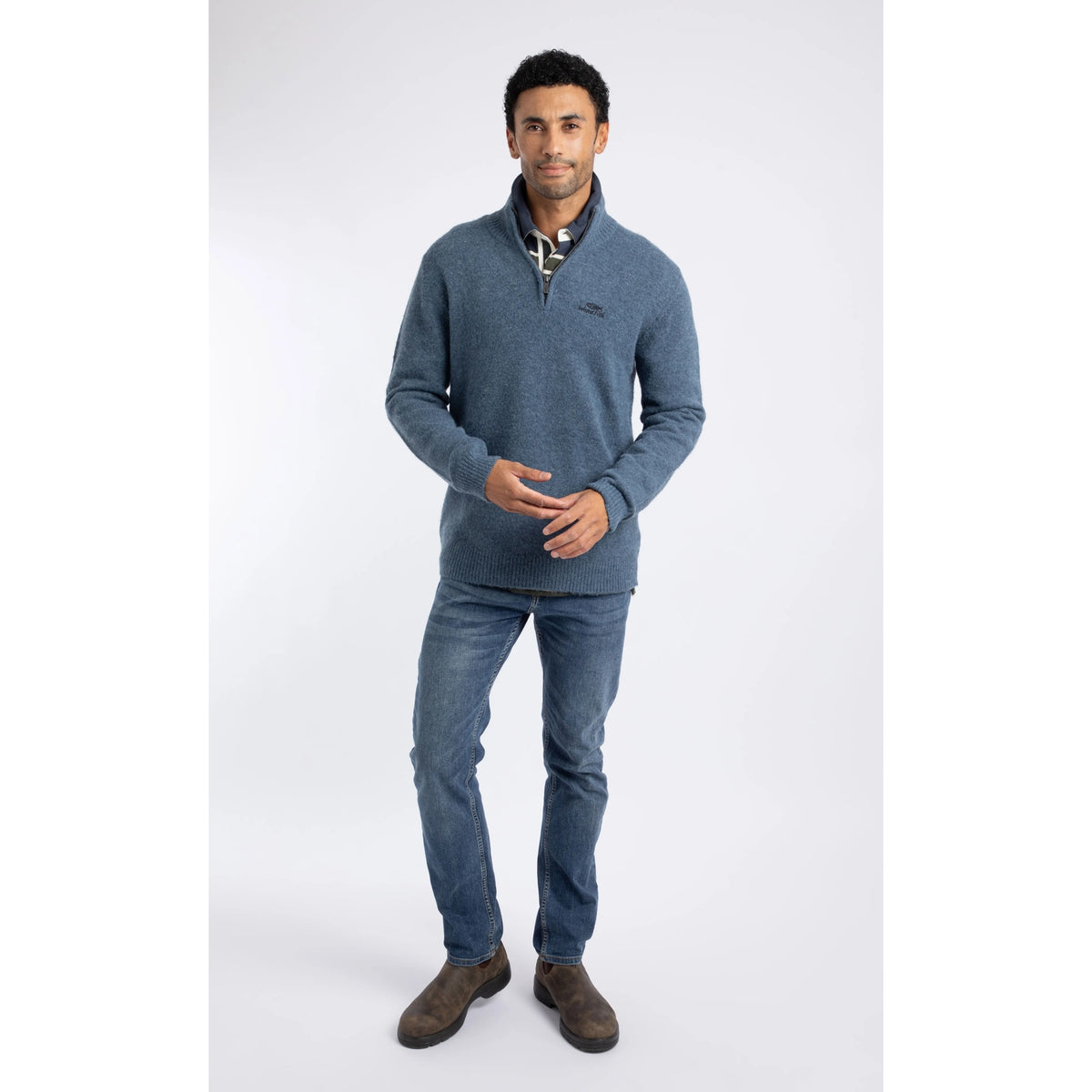 Front view of a man wearing a Weird Fish 1/4 zip Altwood knitted jumper in Ash Blue with blue jeans and brown boots.