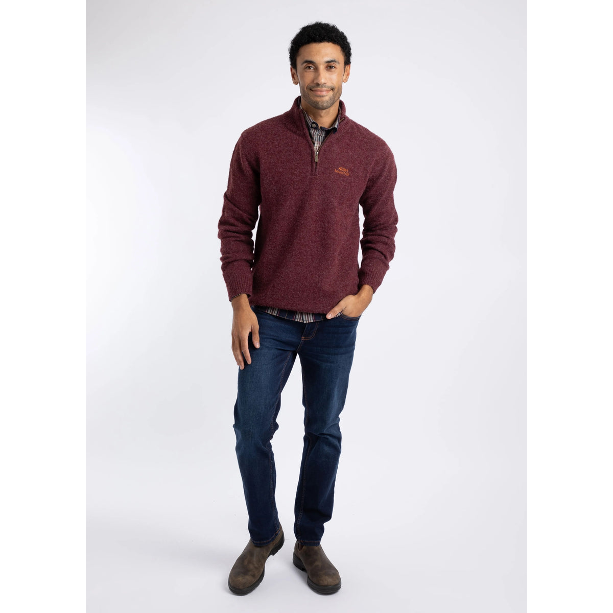 Front view of a man wearing a Weird Fish 1/4 zip Altwood knitted jumper in Garnet Red with blue jeans and brown boots.