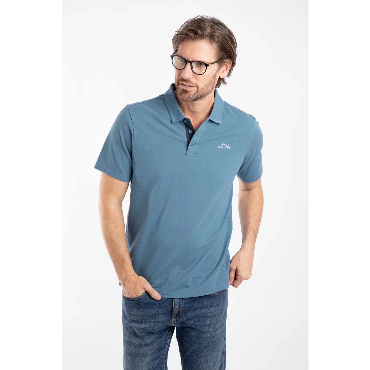 Front view of a man wearing a short sleeve Weird Fish Miles pique polo shirt in Faded Blue.