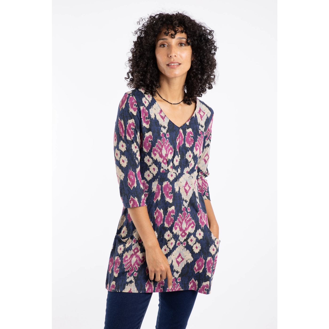 Woman wearing a Weird Fish Arielle tunic in Petrol Blue with a pink-purple abstract pattern on a white background