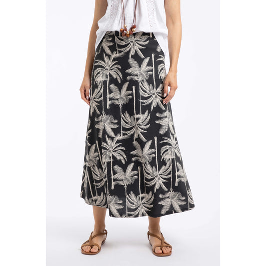 Main front view of a woman wearing a Weird Fish Eloriah midi jersey skirt in black with a beige palm tree pattern.