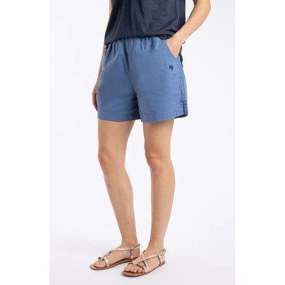 Front view of a woman wearing a pair of Weird Fish Jardin elastic waist twill cotton shorts in Faded Blue with hip pockets and small embroidered logo.